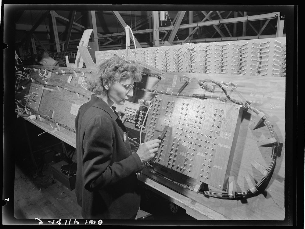 Boeing aircraft plant, Seattle, Washington. Production of B-17 (Flying Fortress) bombing planes. Girl checking electrical…