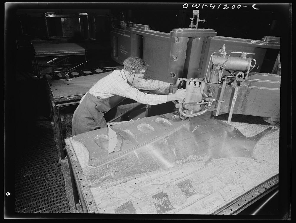 Boeing aircraft plant, Seattle, Washington. Production of B-17 (Flying Fortress) bombing planes. Worker operating a routing…