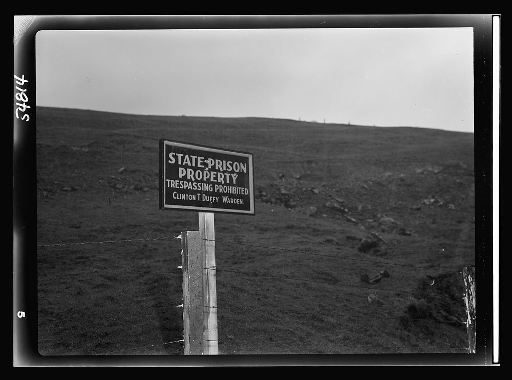 One of many similar signs strung along the fence enclosing San Quentin penitentiary grounds. Sourced from the Library of…