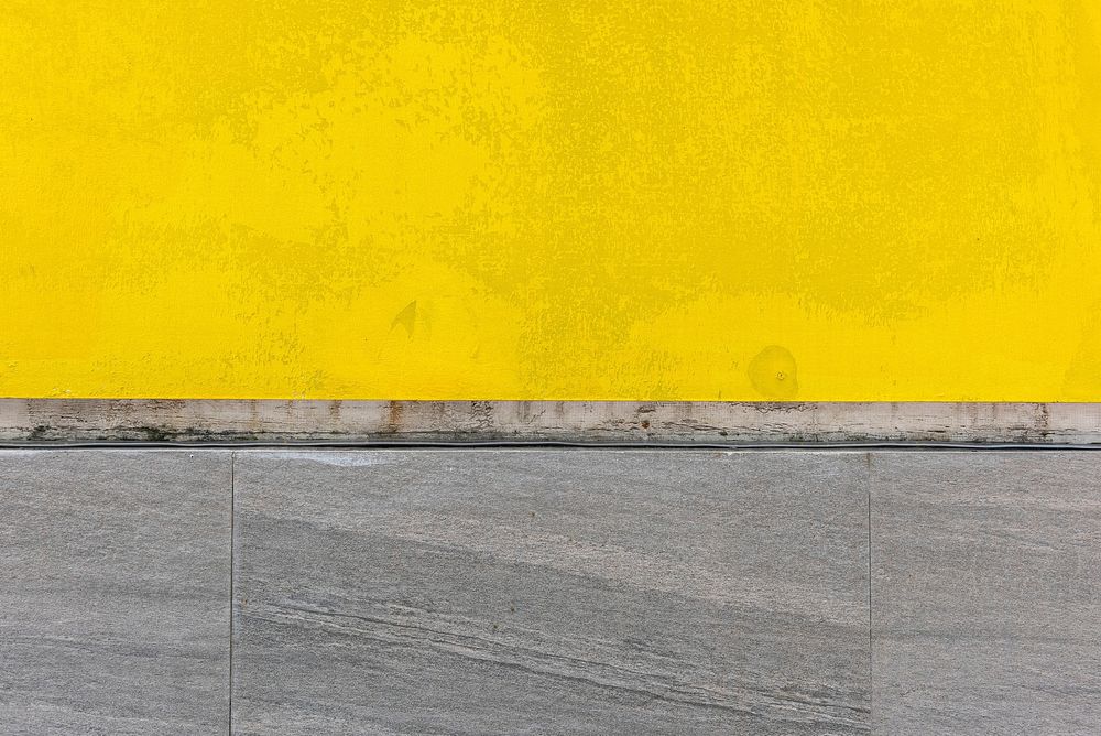 Mustard yellow textured background with gray footpath