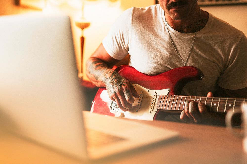 Tattooed man practicing electric guitar at home psd