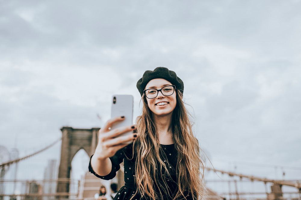 Woman taking selfie with The Brooklyn Bridge, USA, white tone filter