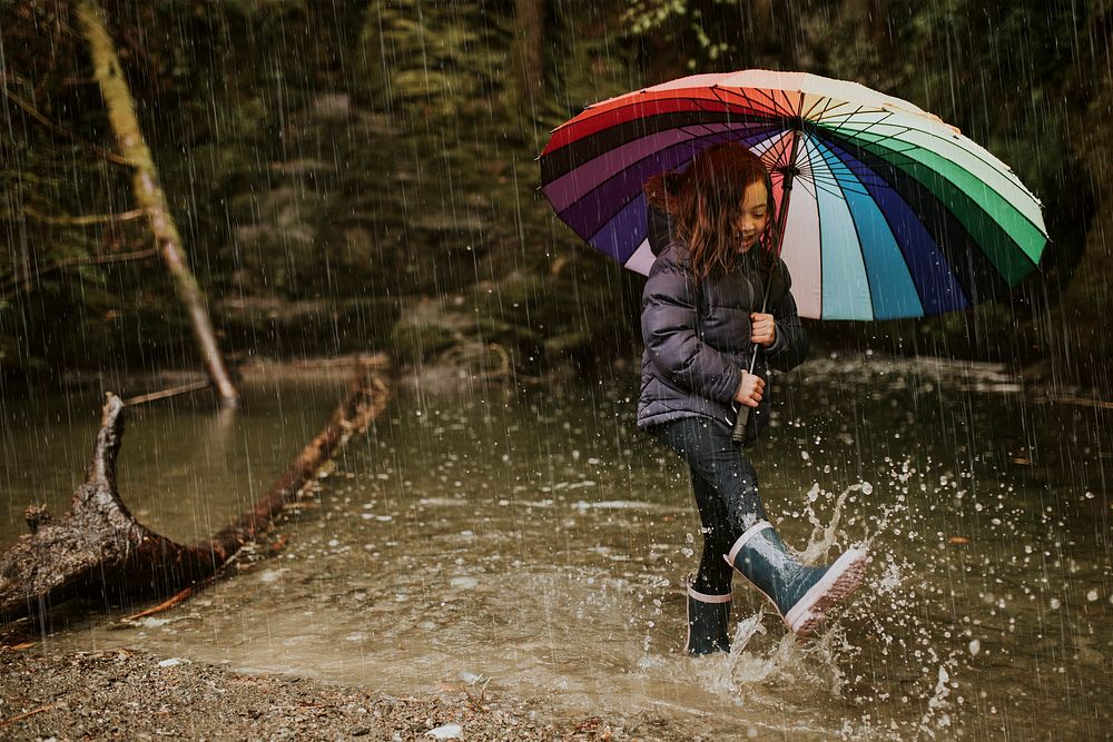 Little girl using an umbrella in stream on a rainy day