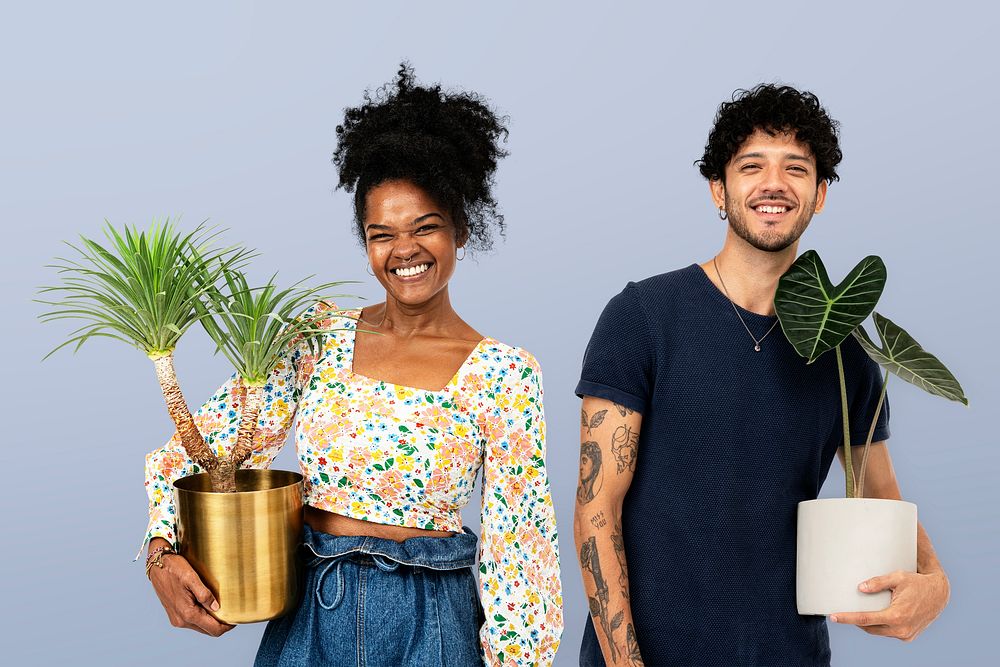 Plant parent couple holding potted houseplants