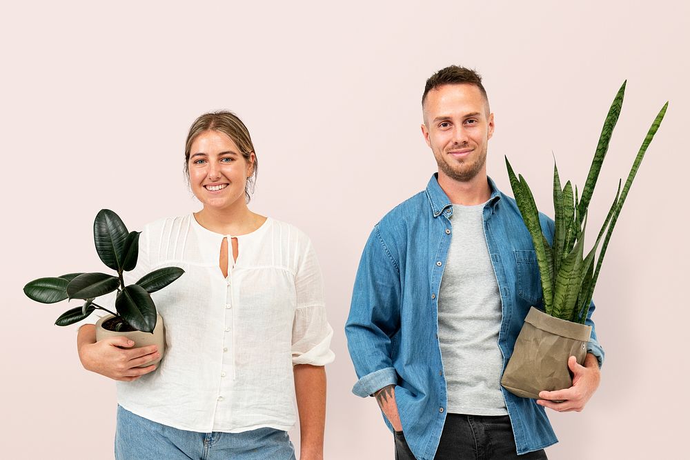 Plant parent couple holding potted houseplants