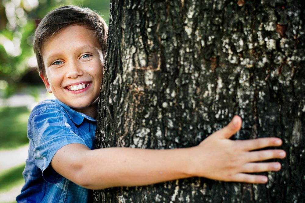 Cheerful boy hugging tree to save environment