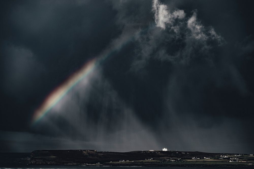 Rainbow under dark clouds, sky, sea. Original public domain image from Wikimedia Commons