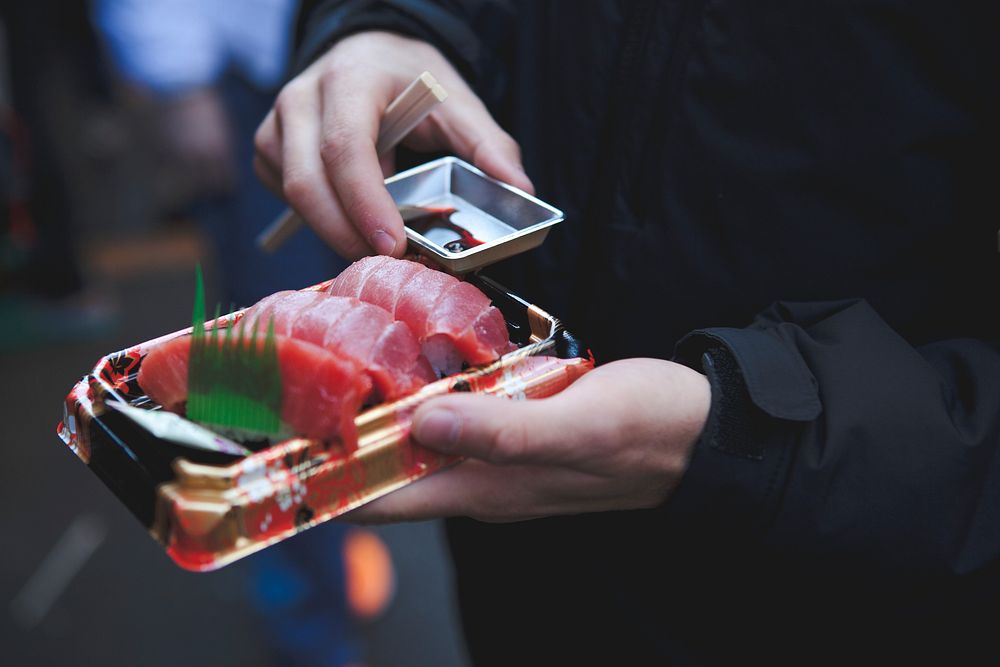 Person holds fresh sashimi with fish from a sushi restaurant. Original public domain image from Wikimedia Commons