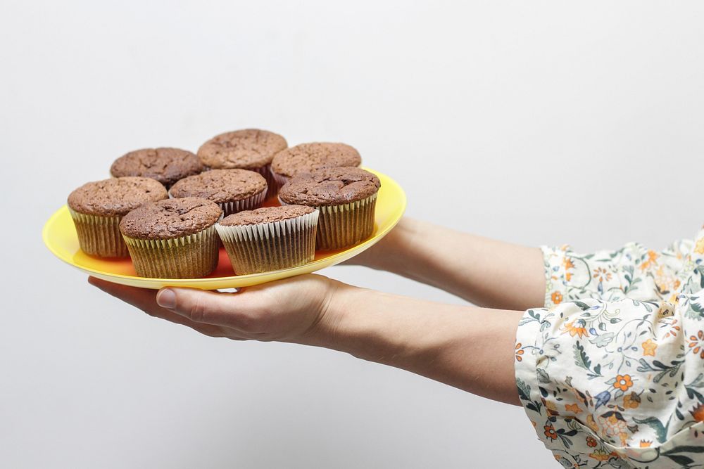 A person holding a tray full of cupcakes. Original public domain image from Wikimedia Commons