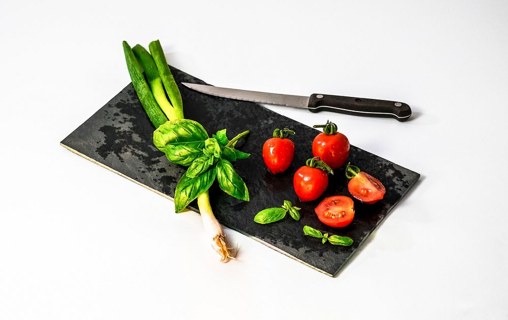 Green onion, basil and tomatoes on a black cutting board. Original public domain image from Wikimedia Commons