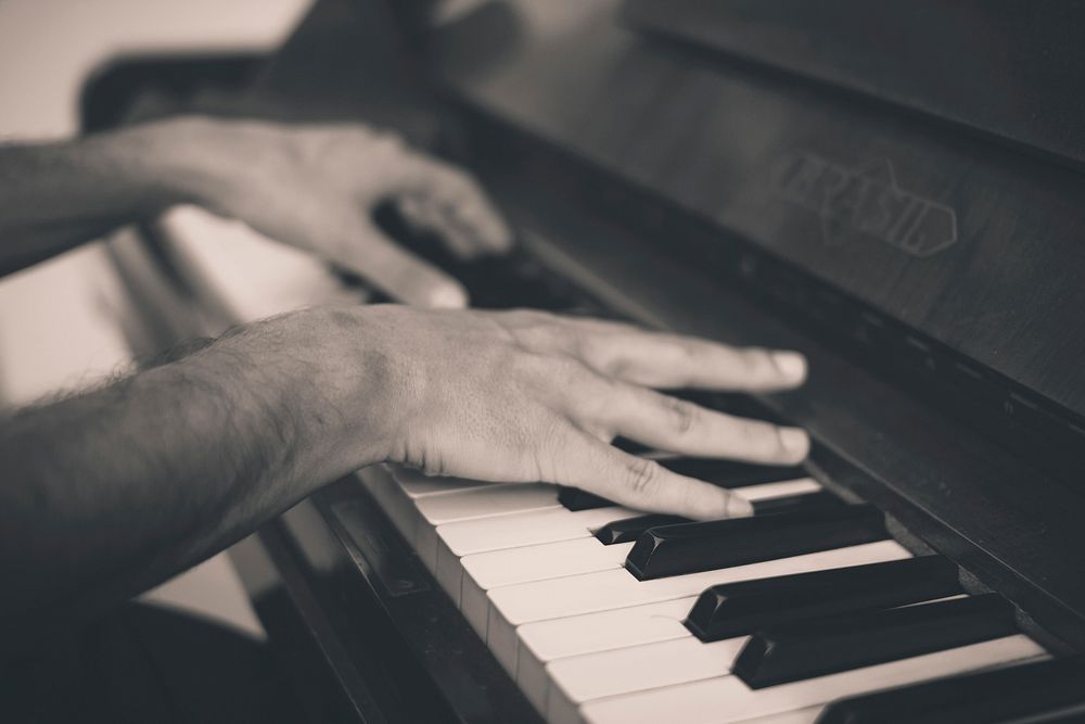 A black-and-white shot of a man's hands playing the piano. Original public domain image from Wikimedia Commons