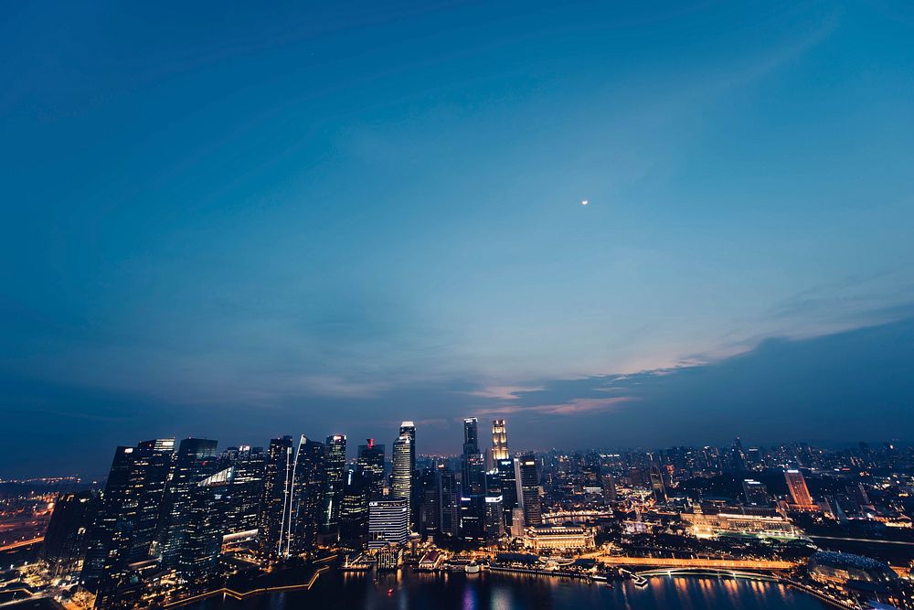 A panoramic shot of the skyscrapers and skyline of Singapore at nightfall.. Original public domain image from Wikimedia…