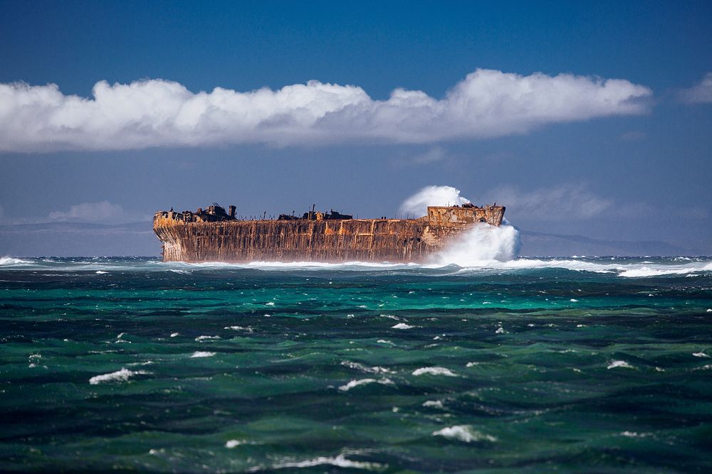An old, rusty ship sailing through the deep, green ocean in Lanai. Original public domain image from Wikimedia Commons