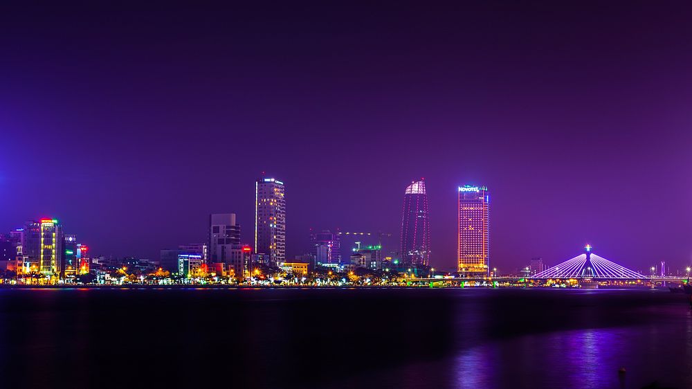 The bright skyline of Da Nang in Vietnam seen from the river at night. Original public domain image from Wikimedia Commons