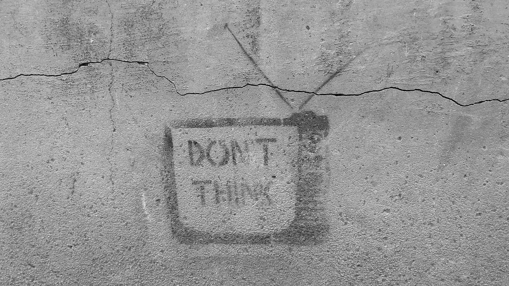 A faded “don't think" graffiti with a television on a gray wall. Original public domain image from Wikimedia Commons
