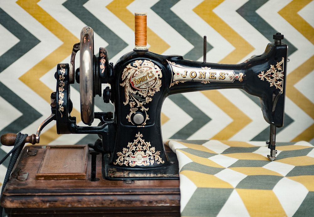 The side view of an old vintage sewing machine sewing on a patterned fabric in cambridge.. Original public domain image from…