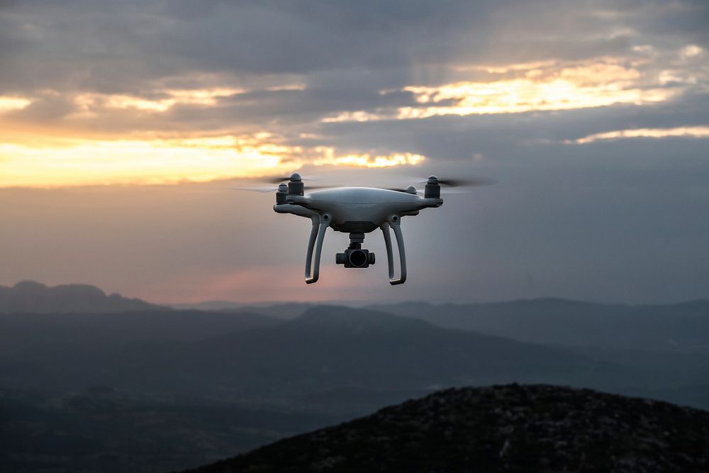 An aerial shot of a drone in flight over hilly terrain in Greece during a cloud covered sunrise-or-sunset. Original public…