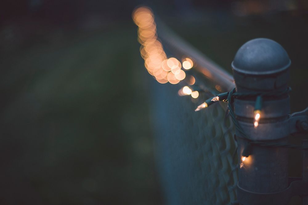 Metal fence post with bokeh string of Christmas lights. Original public domain image from Wikimedia Commons
