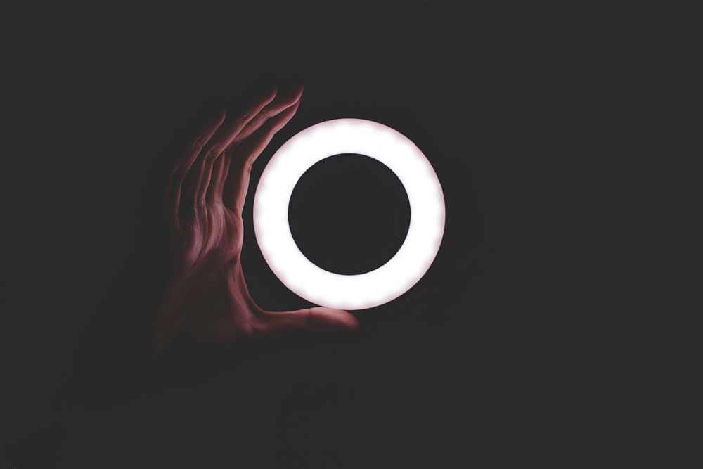A hand taking the shape of a circle light in a black background. Original public domain image from Wikimedia Commons