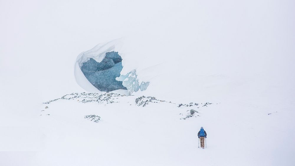 A landscape of a hiker walking in the snow to a ice cave. Original public domain image from Wikimedia Commons