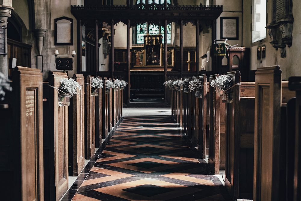Church aisle with wooden benches and tile floor leading towards the wedding altar. Original public domain image from…