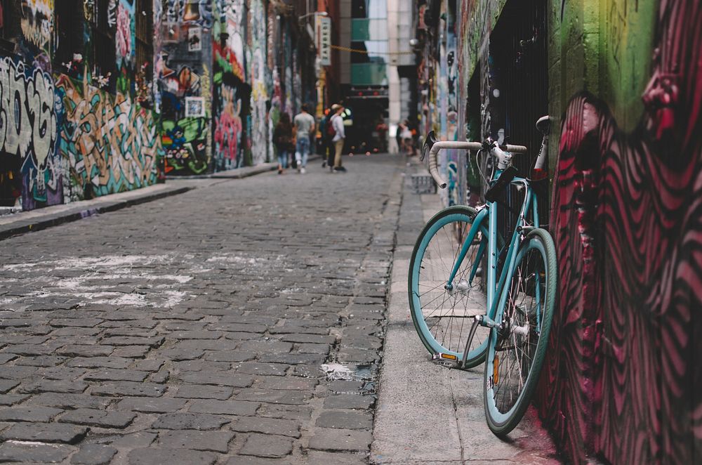 A blue bicycle propped against a wall in a graffiti-lined alleyway in Hosier Lane. Original public domain image from…