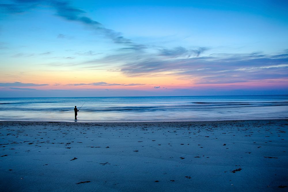 Man fishing at the sand beach after sunset at Corolla, North Carolina, United States. Original public domain image from…