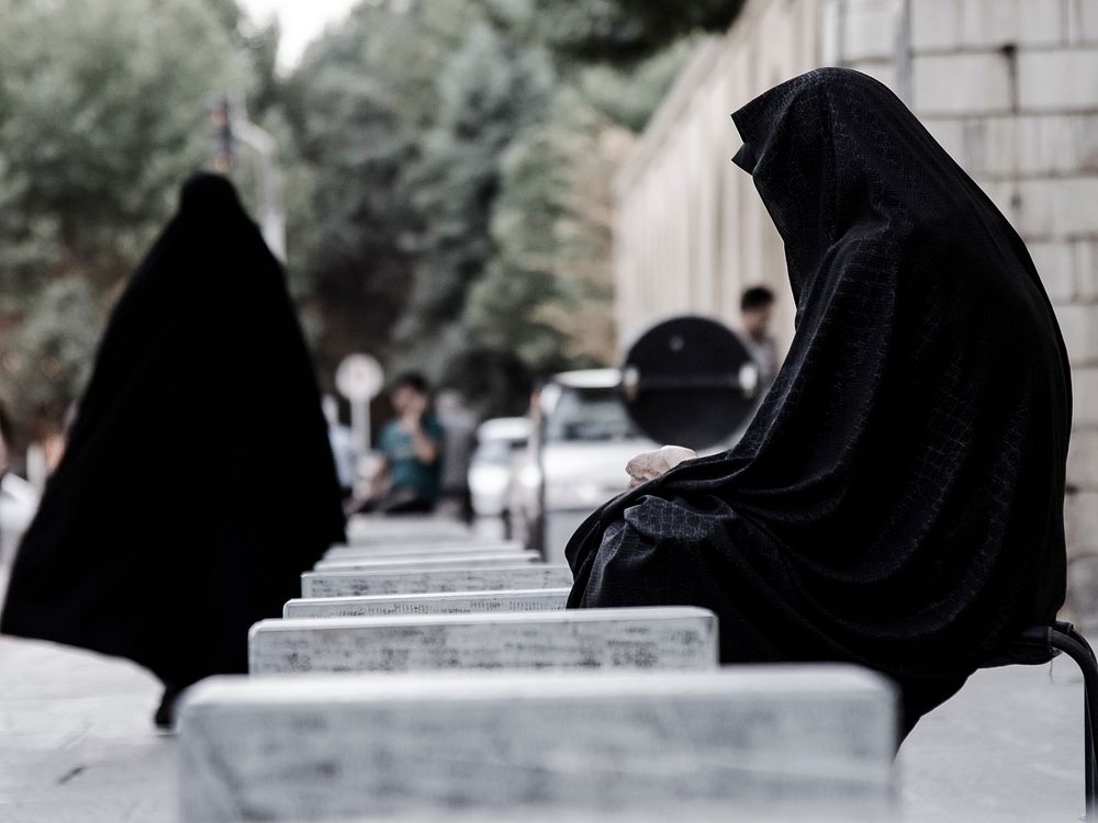 People wearing black burka outfits at a city square in Iran. Original public domain image from Wikimedia Commons