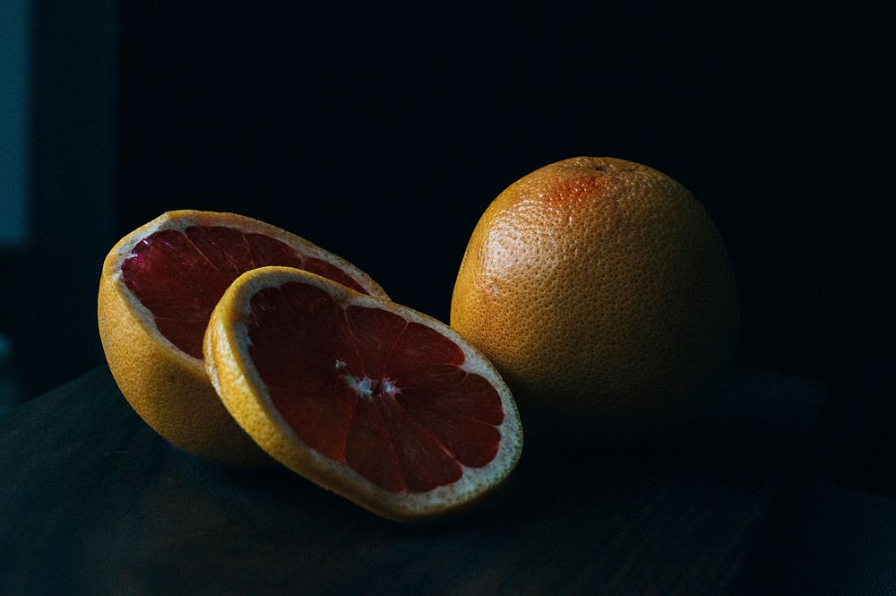 Slices of fresh grapefruit on a black backdrop. Original public domain image from Wikimedia Commons