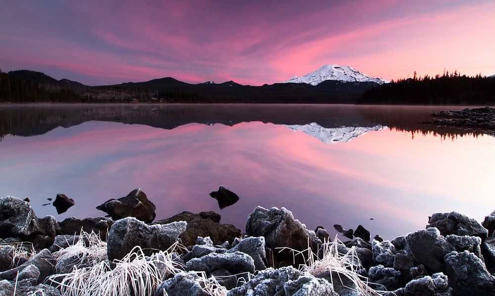 Surreal pink sky reflects in still waters near a mountain landscape. Original public domain image from Wikimedia Commons