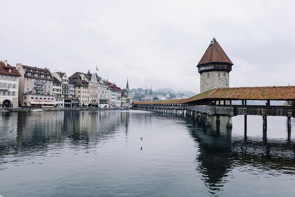 View of buildings and a bridge at the lakeside in Lucerne, Switzerland on a foggy day. Original public domain image from…