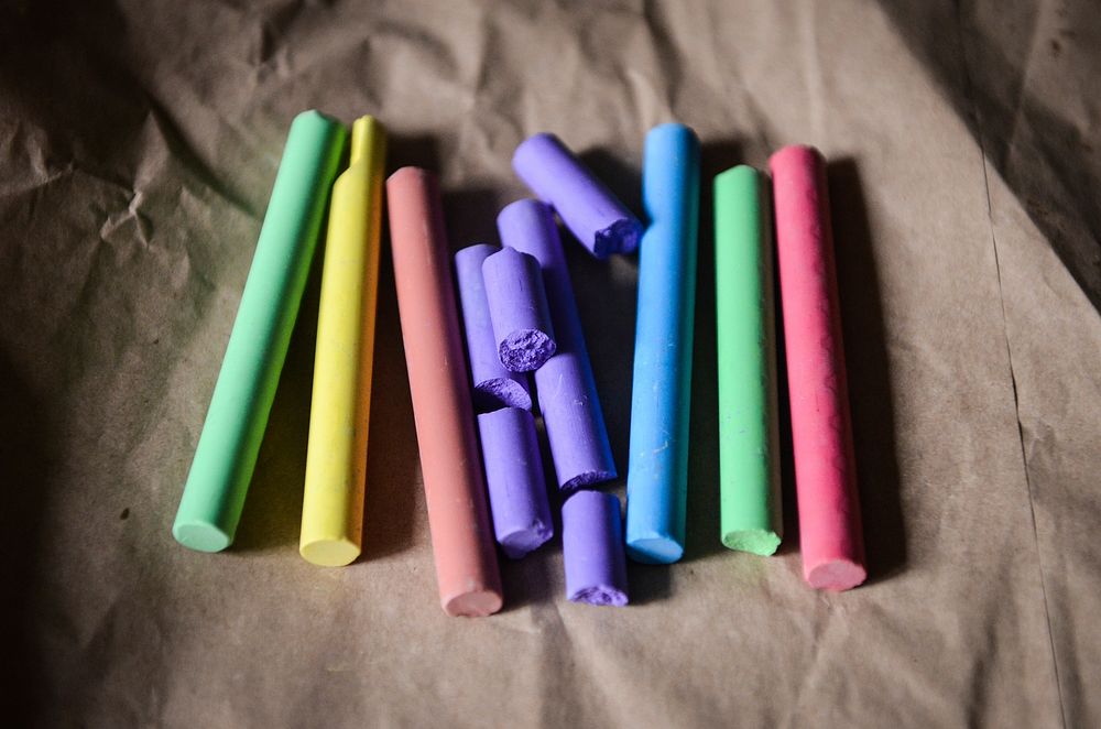 Close up of chalk crayons arranged in rainbow colours on baking paper. Original public domain image from Wikimedia Commons