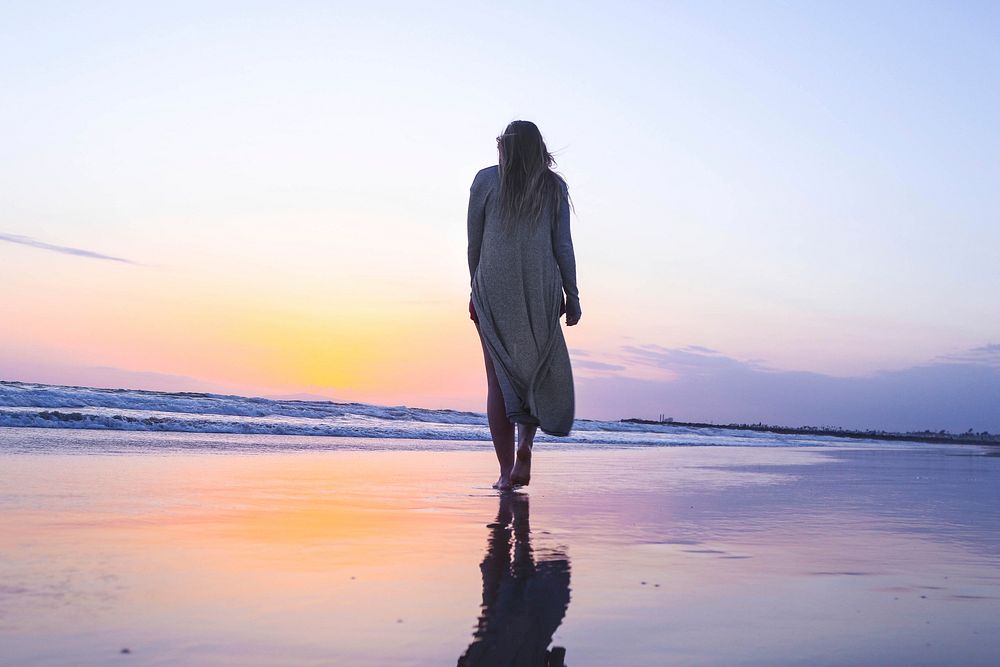 Woman walking on a wet sand beach towards the sunset at Newport Beach. Original public domain image from Wikimedia Commons