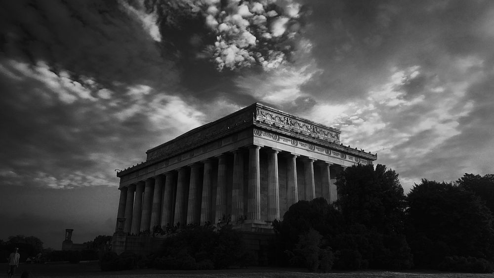 Black and white long shot of classic ancient building with pillars, cloudy sky and trees. Original public domain image from…