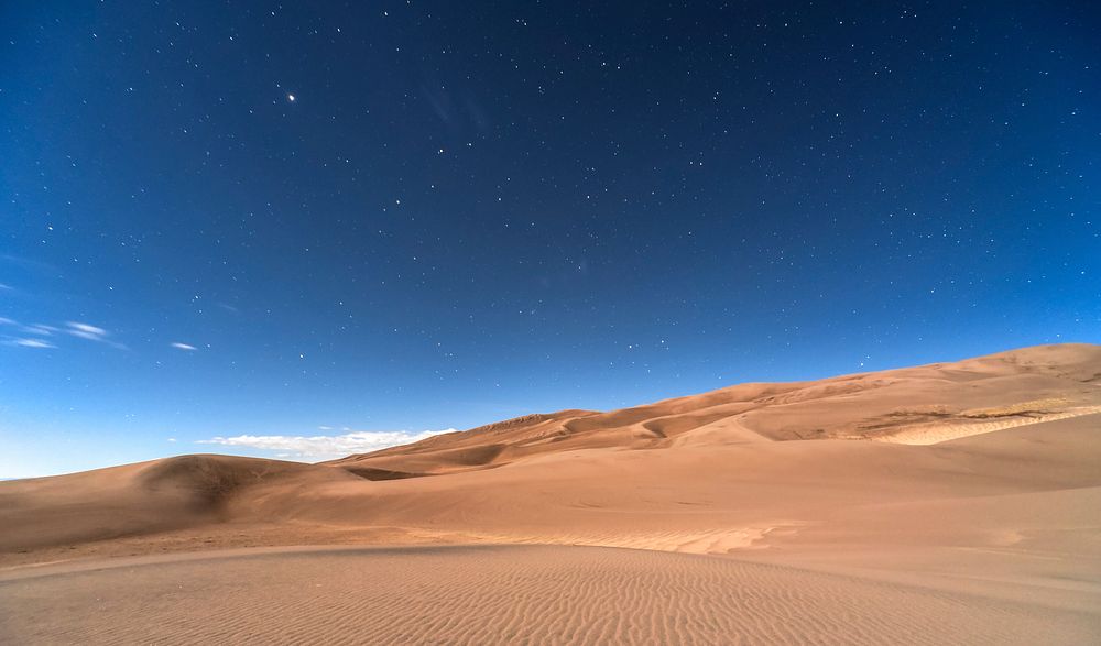 Stars in the clear night sky over a sandy desert in Colorado. Original public domain image from Wikimedia Commons