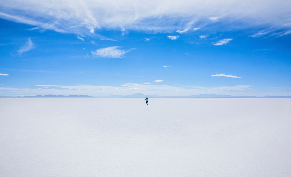 Hiker walks alone toward the desert horizon in Uyuni Salt Flat. Original public domain image from Wikimedia Commons