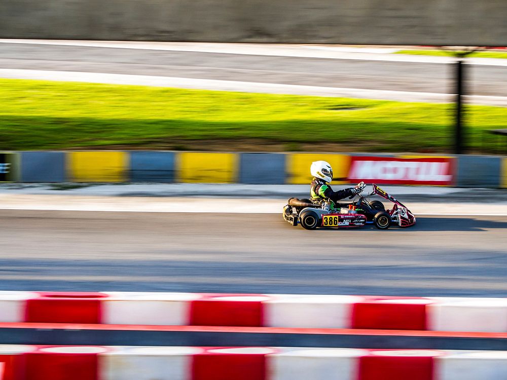 A blurry shot of a person driving a go-kart on race track. Original public domain image from Wikimedia Commons