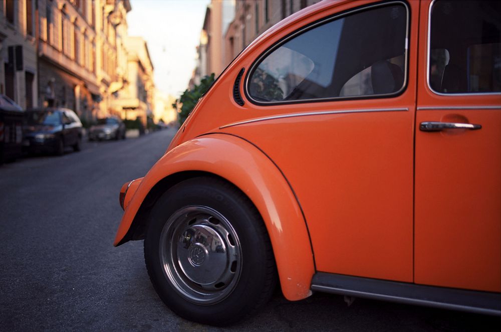 Orange vintage Volkswagen Beetle with a reflection in the back window.. Original public domain image from Wikimedia Commons