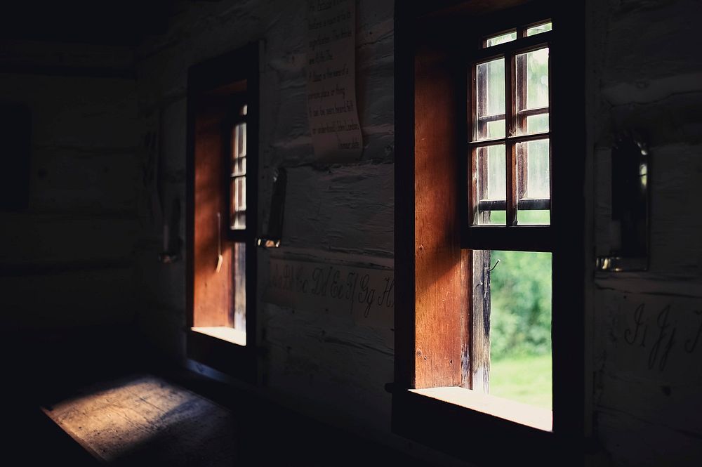 Dim shot inside an old building with sunlight coming in through open wooden windows. Original public domain image from…