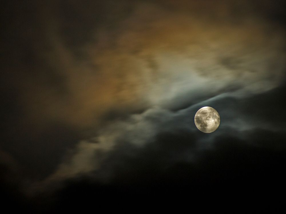 A cloudy night sky with a full moon. Original public domain image from Wikimedia Commons