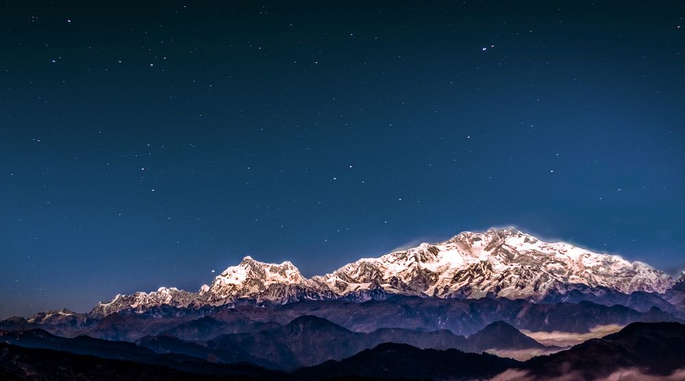 Snow covered mountains at Kanchenjunga South Peak during a starry night sky. Original public domain image from Wikimedia…