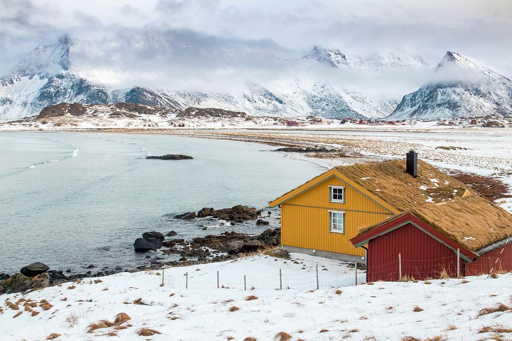 Cabins with the ocean, snowy mountains. Original public domain image from Wikimedia Commons