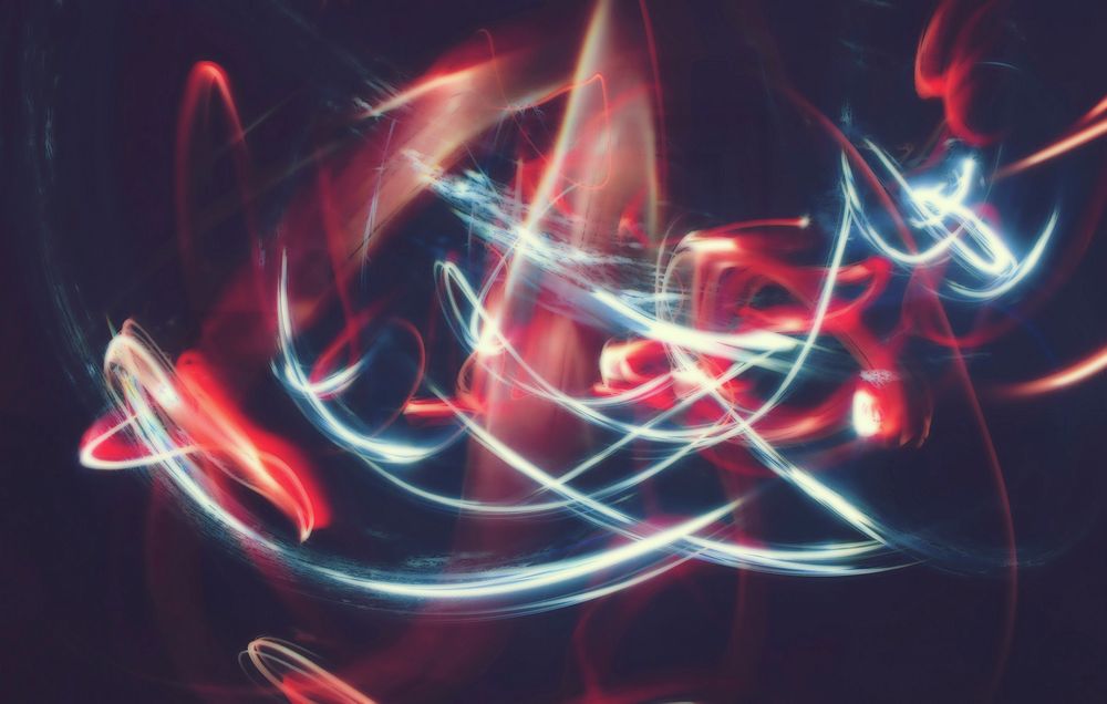 White and red light trails forming abstract patterns in a dark setting. Original public domain image from Wikimedia Commons