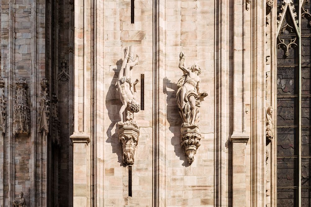 Religious stone church architecture and statue sculptures of human figures at Duomo di Milano. Original public domain image…