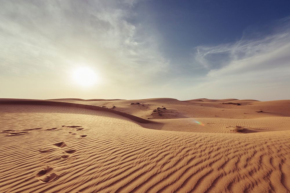 Sun setting over the Muscat horizon, casting shadows on the ripples of the desert sand dunes. Original public domain image…
