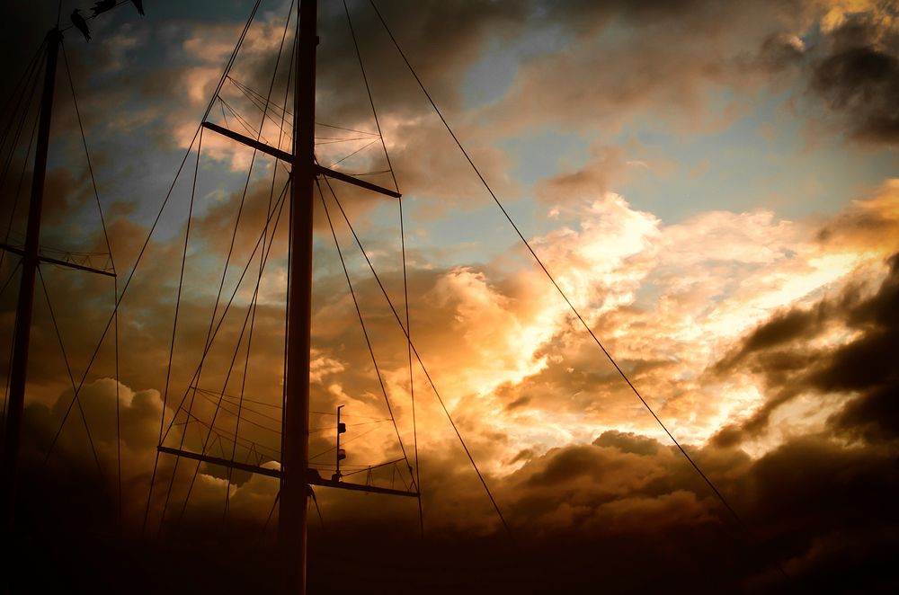 A ship's mast with rigging is set against golden clouds during sunset at La Paz.. Original public domain image from…