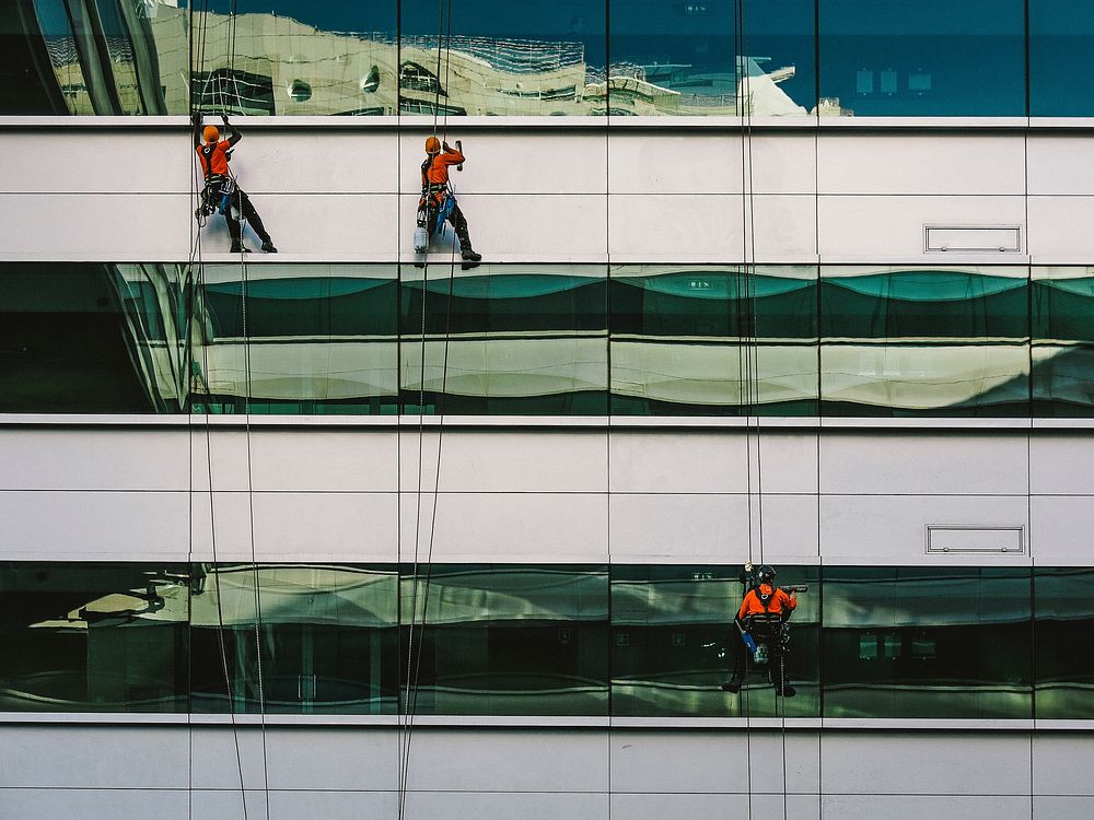 Three window cleaners on ropes on an office building facade. Original public domain image from Wikimedia Commons