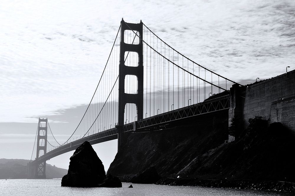 Black and white shot of Golden Gate Bridge in San Francisco from afar with cloudy sky. Original public domain image from…