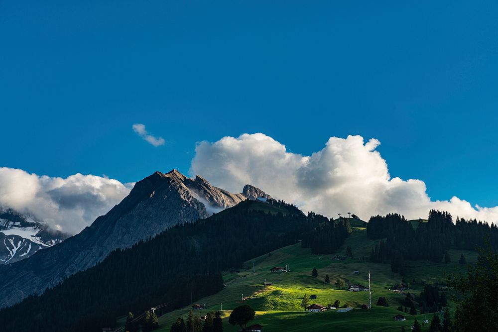 A grassy mountain shot with the clouds beyond the peak in Adelboden village. Original public domain image from Wikimedia…