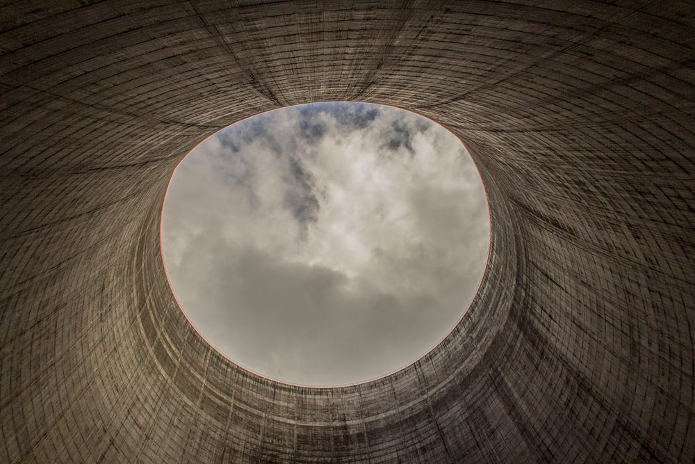A cooling tower with an elliptical hole on top of it showing the clouds in Satsop Nuclear Power Plant. Original public…
